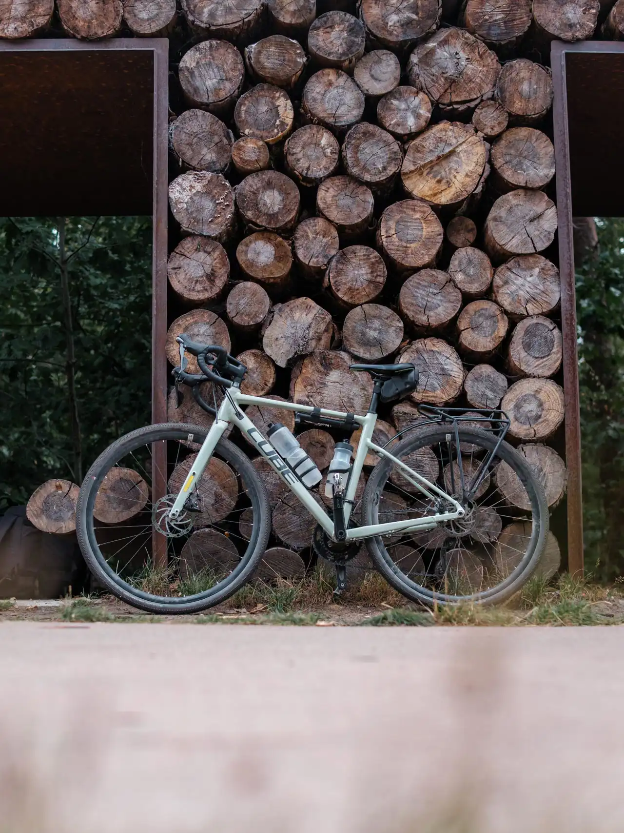 Vélo gravel Cube devant des rondins de bois