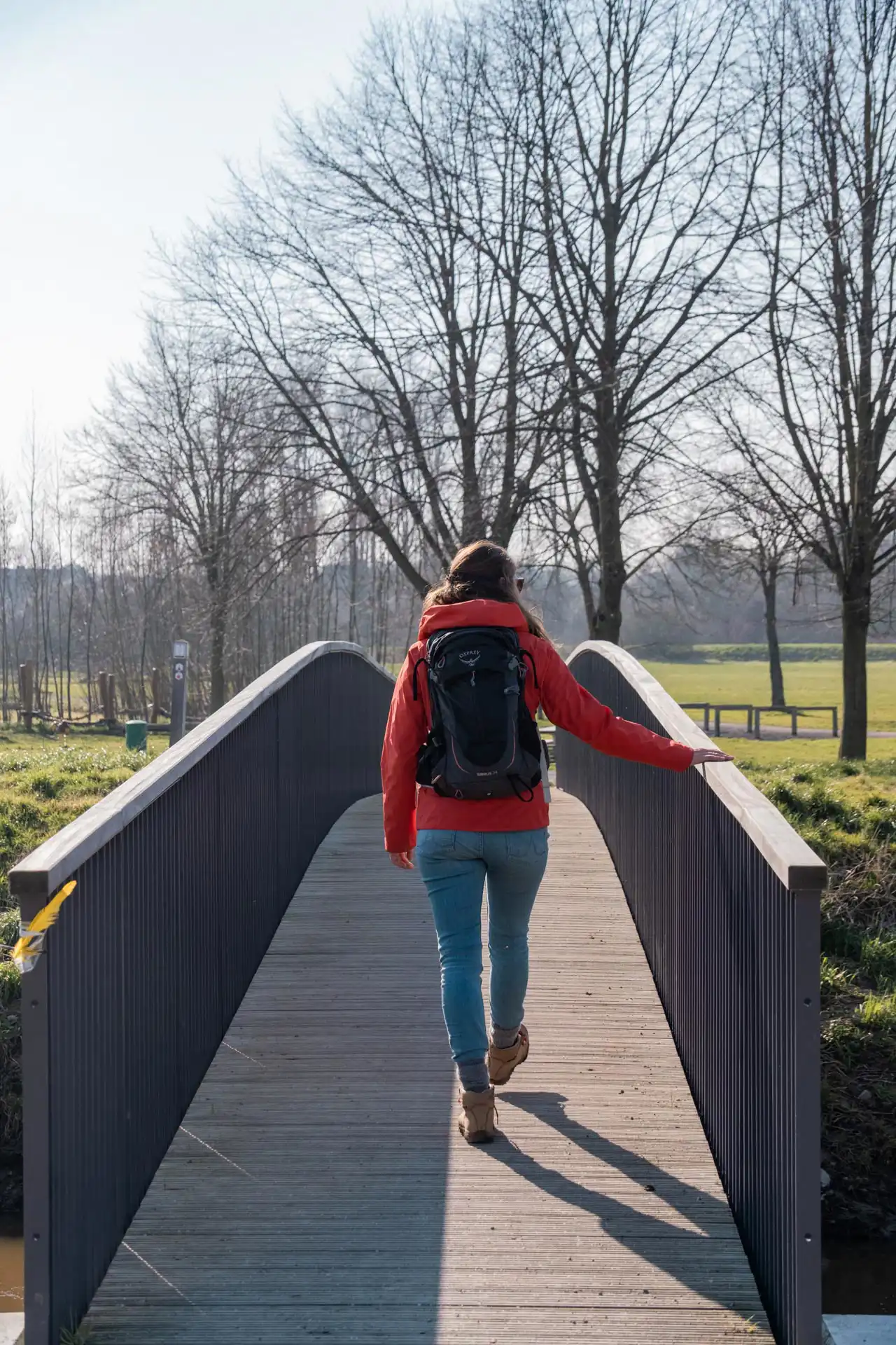 femme de dos marchant sur un pont - Demerbroeken