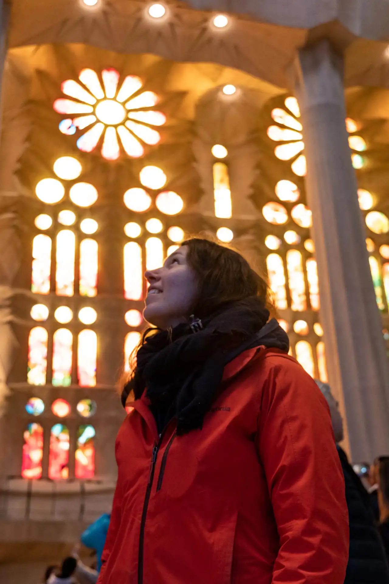 Femme avec une veste rouge observant l'intérieur de la Sagrada Família