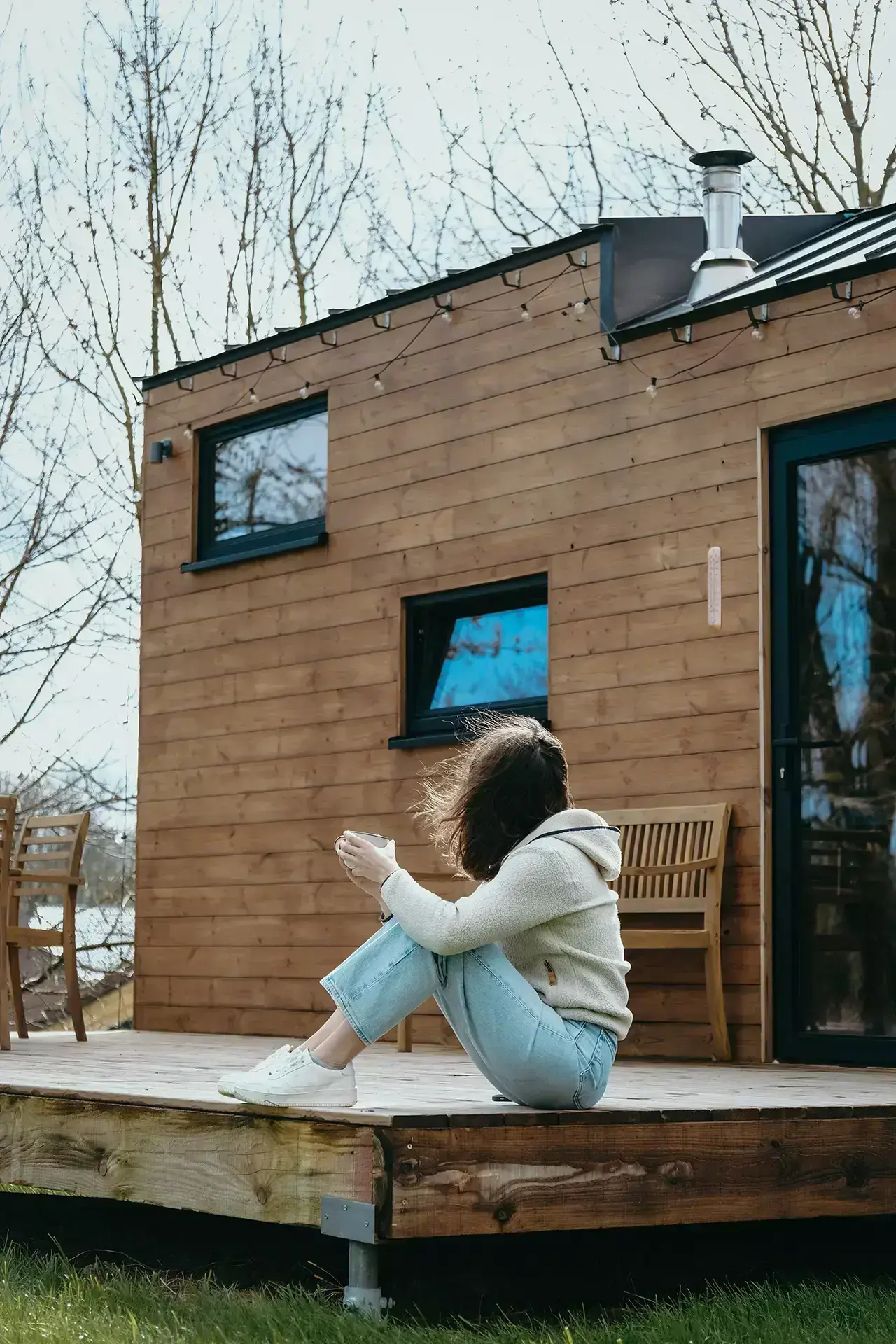 Femme buvant son thé assise sur la terrasse extérieure d'une Tiny House